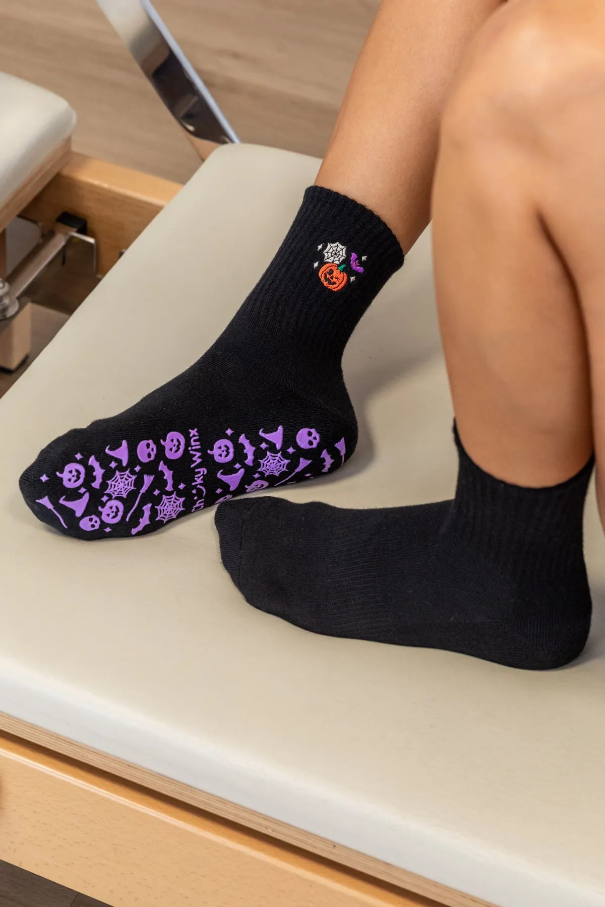 Black crew grip socks with spooky purple Halloween grip featuring webs, bats, and pumpkins by Cheeky Winx. Non-slip sole for reformer, Pilates, yoga, and barre. Australia's best grip socks.
